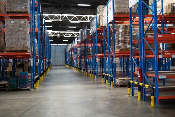 Almacén industrial con racks de almacenamiento de acero optimizados para el manejo de grandes volúmenes y tarimas.
